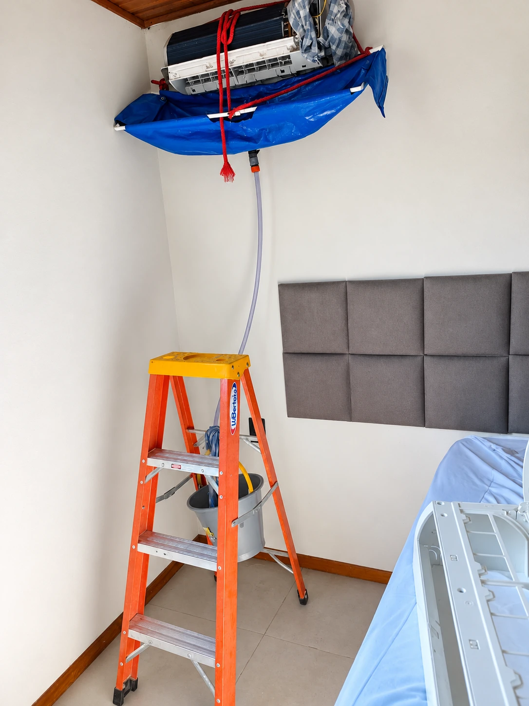Manutenção de ar-condicionado com capa de proteção e escada em ambiente interno