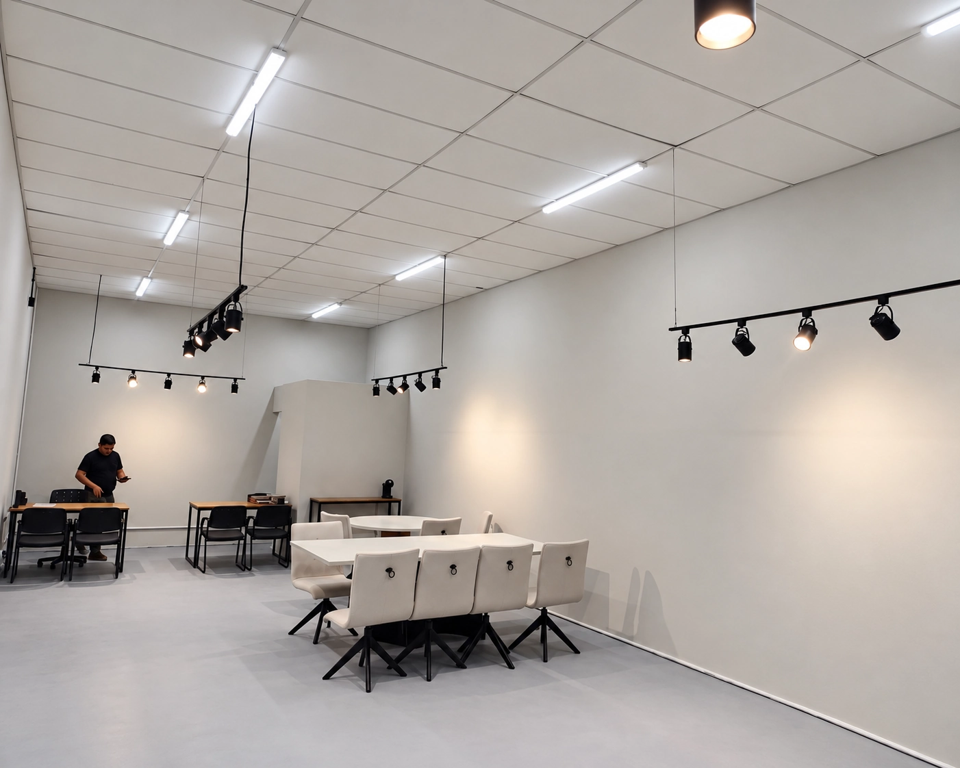 Sala de reuniões iluminada por luminárias lineares e trilhos de spots no teto
